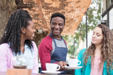 Genç garson iki tatlı kadına servis yapıyor.