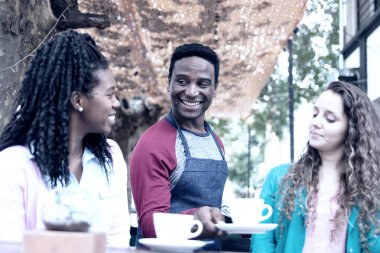 Genç garson iki tatlı kadına servis yapıyor.