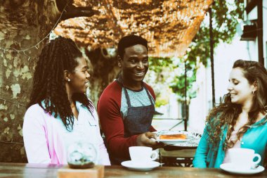 Genç garson iki tatlı kadına servis yapıyor.