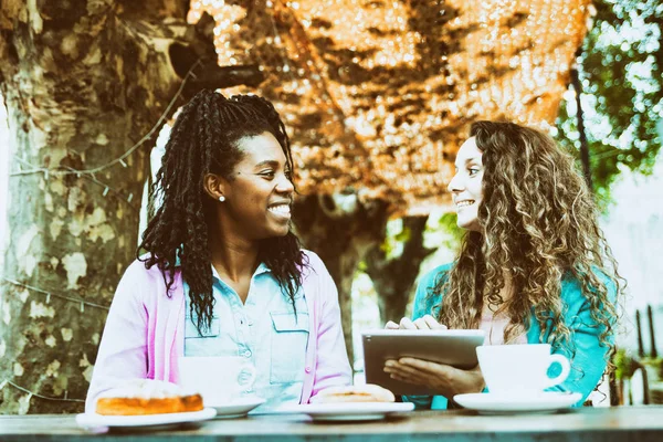 Two girlfriends watch the tablet at the Coffee Bakery shop