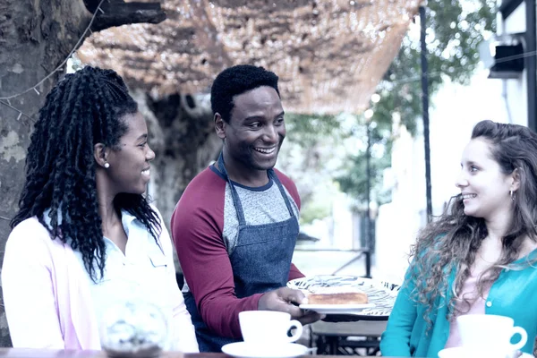 Young waiter serves two cute women