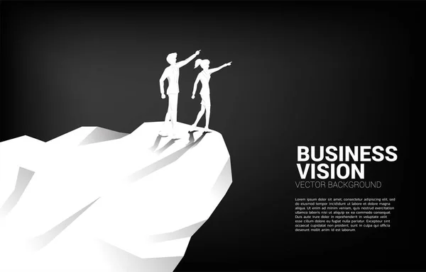 Силует бізнесмена і бізнес-леді вказують вперед від гірської скелі. Початок місії з бачення бізнес-ринку — стоковий вектор