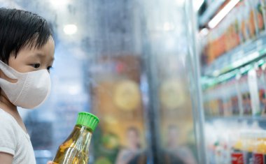 2 yaşında Asyalı bir çocuk süpermarkette maske alışverişi yapıyor. Salgında yaşam ve yeni normal yaşam kavramı..
