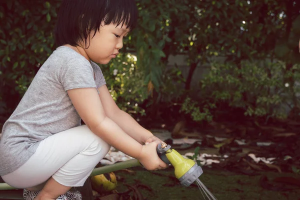 Funny moment of 3 Year old asian kid playing water with garden hose in backyard. Background concept  for play time and summer of children.