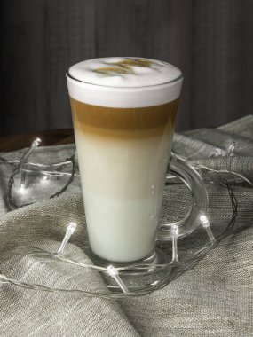 ışıkların arka planında cam bir kabın içinde latto macchiato kahve