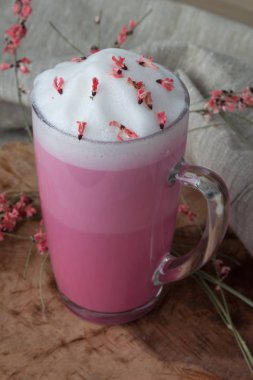 hava köpük ile kurutulmuş çiçekler ile dekore ahşap bir destek üzerinde bir cam fincan pembe kahve latte macchiato