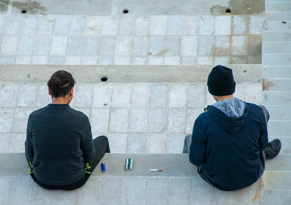 Merdivenlerde oturan iki çocuk sigara içmeye hazırlanıyor.