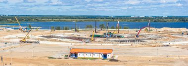 İnşaat alanında büyük bir stadyum Panoraması. Kule Vinçler, çerçeve, yekpare kat, sütun, inşaat kampı ve İnşaat ekipmanları, çok sayıda işçi.