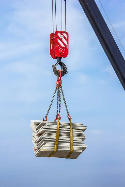 The crane lifts a heavy load on a hook to a great height.