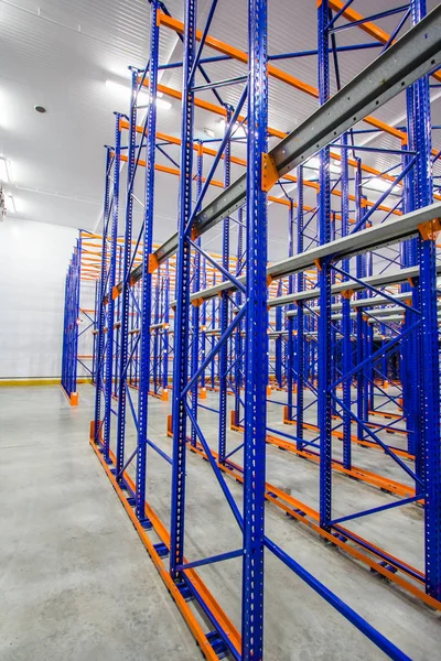 Huge areas for storage of goods, storage rack, blue and orange metal shelves for storing goods in a large warehouse complex, concrete floor, vertical storage,