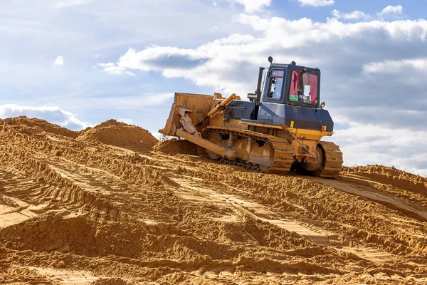 buldozer şantiyede hafriyat işleri yapar, gökyüzüne kadar kum büyük bir dağ tırmıklar