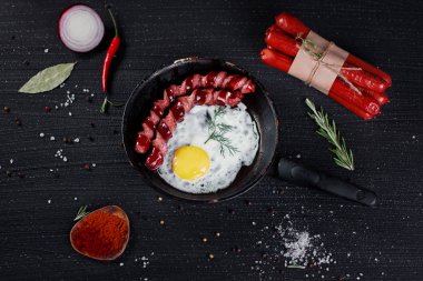 Baharat ve siyah arka plan üzerine biberiye ile çırpılmış yumurta ve kızarmış sosis