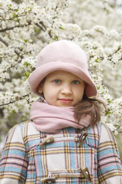  Bahar çiçek açan ağaçların arka planda hafif bir kaput küçük bir kızın portresi.