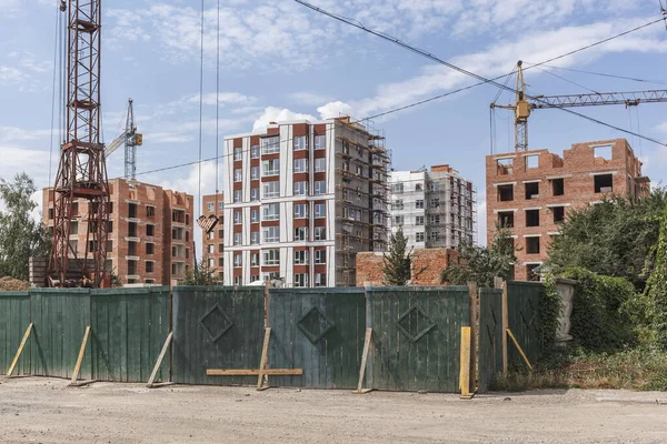 Çok katlı yeni bir binanın inşaatı. Yeşil çitin arkasındaki inşaat alanında..