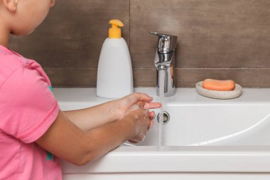 Küçük kız ellerini banyoda sabunla yıkıyor. Enfeksiyon ve virüslere karşı koruma.