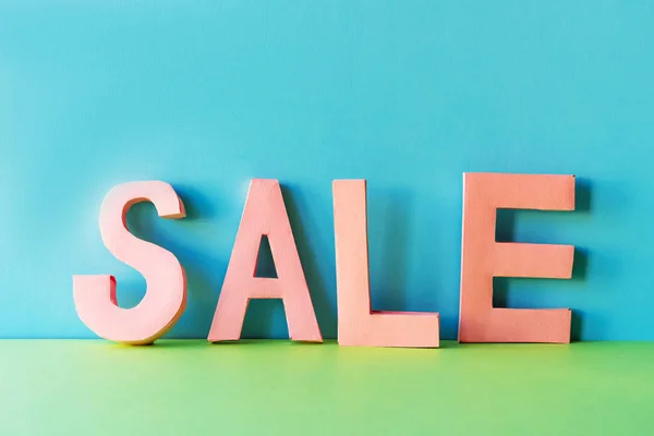 From paper craft pink letters, the word SALE is composed.