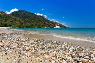 Aninuan beach, Puerto Galera, Oriental Mindoro in the Philippines, landscape view with cobbles and shells at the foreground. clipart