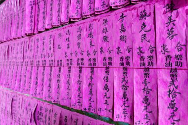 Pink paper prayer flags or prayer slips with names in Chinese black ink in the Thien Hau Temple of Cho Lon (Chinatown), district 5,  Saigon, Ho Chi Minh City, Vietnam. clipart