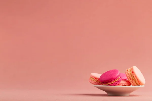 큰 카피 스페이스가있는 분홍색 식탁보 배경 위에 작은 접시에 프랑스 핑크 마카롱 또는 마카롱 스택. — 스톡 사진