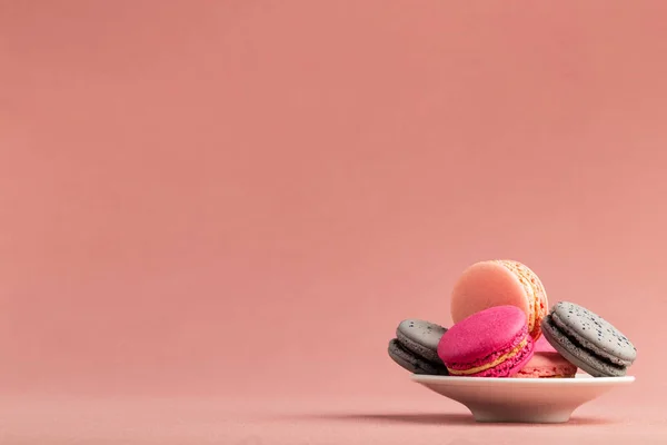 Pile de macarons ou macarons roses et gris français, dans une petite assiette sur un fond de nappe rose avec un grand espace de copie . — Photo