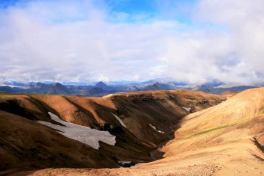 Landmannalaugar Milli Parkı'nda kar ve yeşil dağlar ile turuncu kum tepeler, İzlanda.