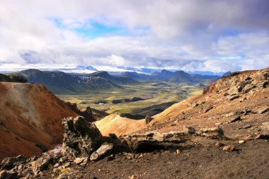 Landmannalaugar Ulusal Parkı'ndaki turuncu kayalar, yeşil vadi, tepeler ve buzullar, İzlanda.