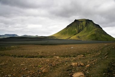 Landmannalaugar Milli Parkı bulutlu bir günde yeşil bir dağ ile siyah ve turuncu kum, İzlanda.