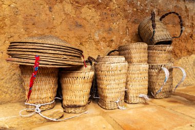 Hmong geleneksel sepet sırt çantaları ve Ha Giang Eyaleti, Kuzey Vietnam geleneksel bir hmong evin girişinde geleneksel Vietnam şapkabir yığın.