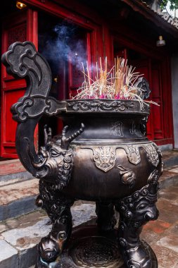 Tütsü, Edebiyat Tapınağı'nda (Quoc Tu Giam), Hanoi, Vietnam'da çelik bir vazoya yapışır. Dikey görünüm.