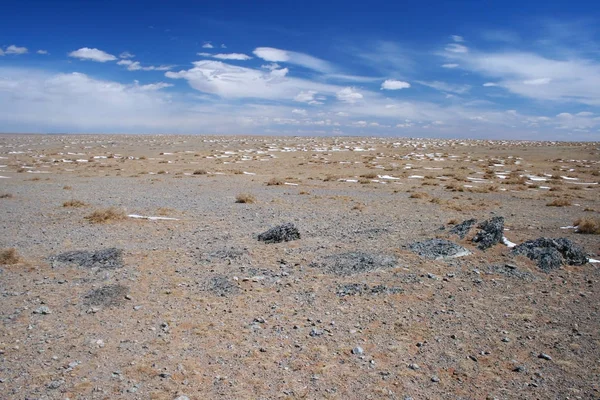 Gobi pouštní krajina se zasněženou skvrnami, béžovým pískem a černými kameny za slunečného dne, Mongolsko. — Stock fotografie