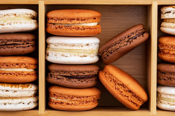 Brown and white french macarons or macaroons, (chocolate, coffee Brown and white french macarons or macaroons, (chocolate, coffee, toffee, salted caramel and vanilla) stacked in a bamboo box. — Stock Photo, Image