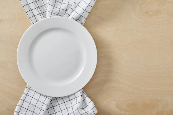 Buňka ubrousek na dřevěný stůl s kopií prostor a bílý prázdný talíř — Stock fotografie