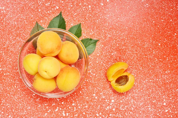 Reife Bio-Aprikosen mit Blättern auf einem Farbtisch. Zutaten zum Kochen. — Stockfoto