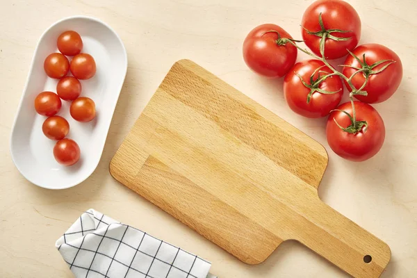 Сырой помидор на столе с нарезанной доской и салфеткой . — стоковое фото