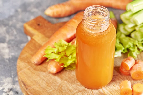 Fresh green celery, juice in bottle on background near the carrots. — Stock Photo, Image