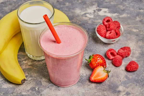 Summer smoothies strawberry,  raspberry ,banana, glass milk on gray background.