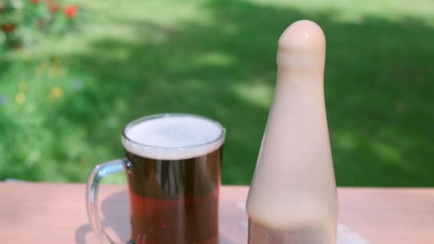 Bière brune fraîche avec bouteille, mousse dans un jardin vert .