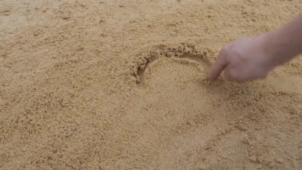 Persoon tekent een inscriptie op zand hart. — Stockvideo