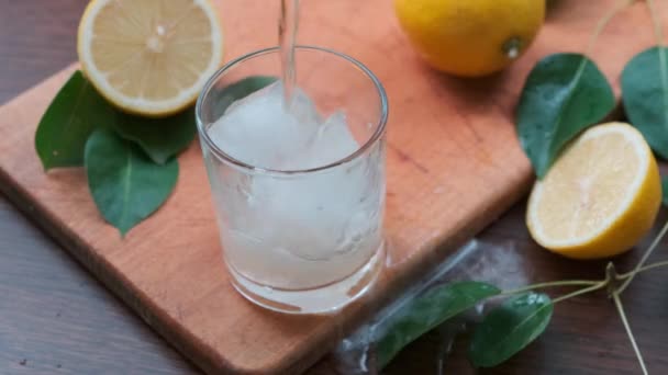 Gießt Zitronensaft aus Krug in Glas auf Holztisch. — Stockvideo