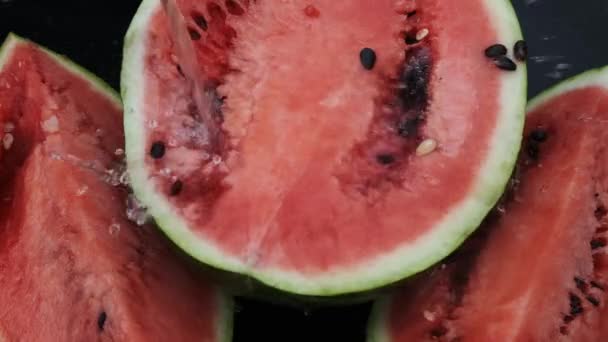 Wassermelone geschnitten auf dunklem Hintergrund. Wasserwelle und Tropfen. — Stockvideo