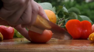 Ahşap tahta üzerinde bir bıçak ile el kesme domates.