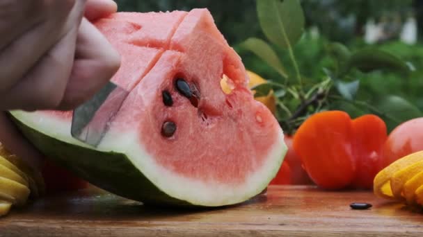 Hand skärning vattenmelon med en kniv på trä kartong. — Stockvideo