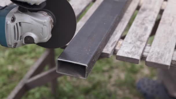 La rectificadora circular de primer plano al aire libre chispa el corte del perfil metálico en el taller . — Vídeos de Stock