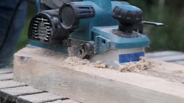 Manos de los planos de carpintero una viga con herramienta cepilladora de madera eléctrica  . — Vídeo de stock