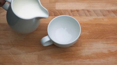 Ahşap bir arka plan üzerinde beyaz bardak süt dökme yakın.