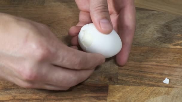 Mannelijke handen reinigt een gekookt kippenei aan boord. — Stockvideo