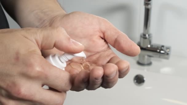 Een man in de badkamer knijpt zeep of room op zijn hand. — Stockvideo