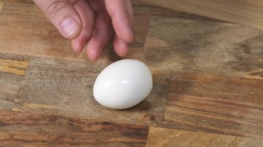 Tahta tahta üzerinde elleri ile sert haşlanmış yumurta Peel.