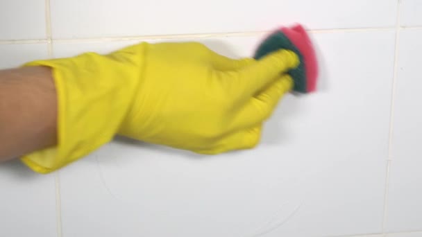 Person in yellow rubber gloves washer is cleaning tiled surface in bathroom . — Stock Video