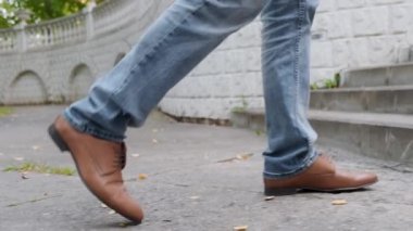 Mavi kotlu, kahverengi deri ayakkabılı, yürüyen adam manzarası.